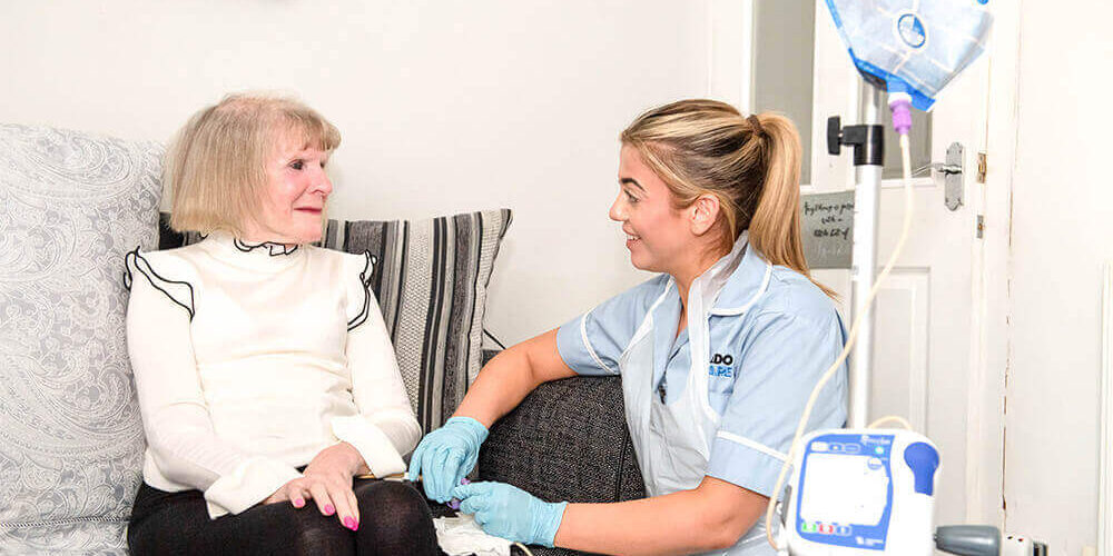 A live-in care assistant delivers nutrition to a live in care client